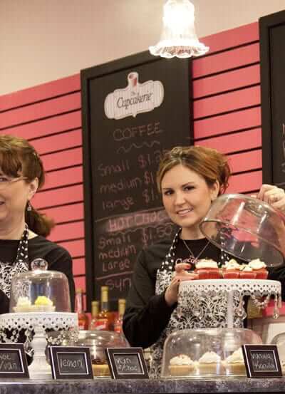 Cupcakerie employees setting up cupcake displays