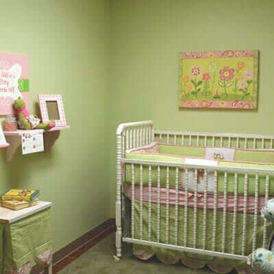 Nursery/ baby bedroom with green walls, furniture, and toys