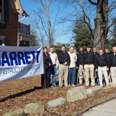 Jarrett Construction Services employees lines up next to a banner with their logo
