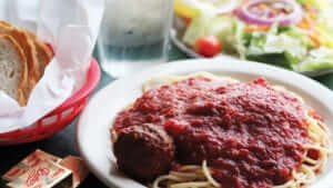 A plate of spaghetti with a meatball.