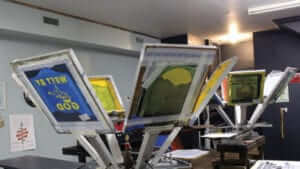 Screens for screen printing hanging to dry with designs on them.