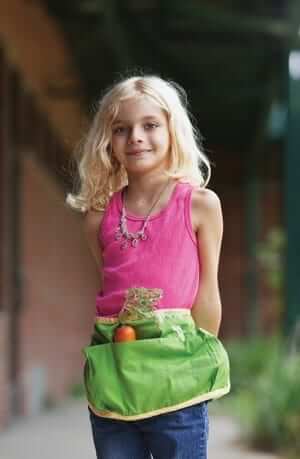 Girl enjoying local produce wearing an apron with a carrot in the pocket
