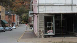 abandoned looking store with sign reading "for sale by owner"