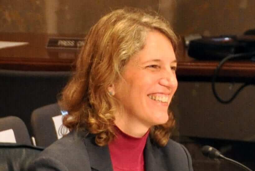 Sylvia Mathews Burwell smiling to someone talking to her off camera
