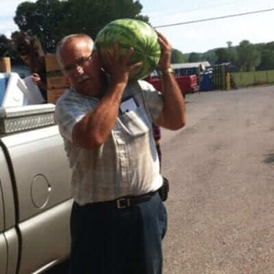 Farmer carrying watermelon.